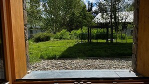Une pièce aux murs en bois, donnant sur un jardin et une pergola.