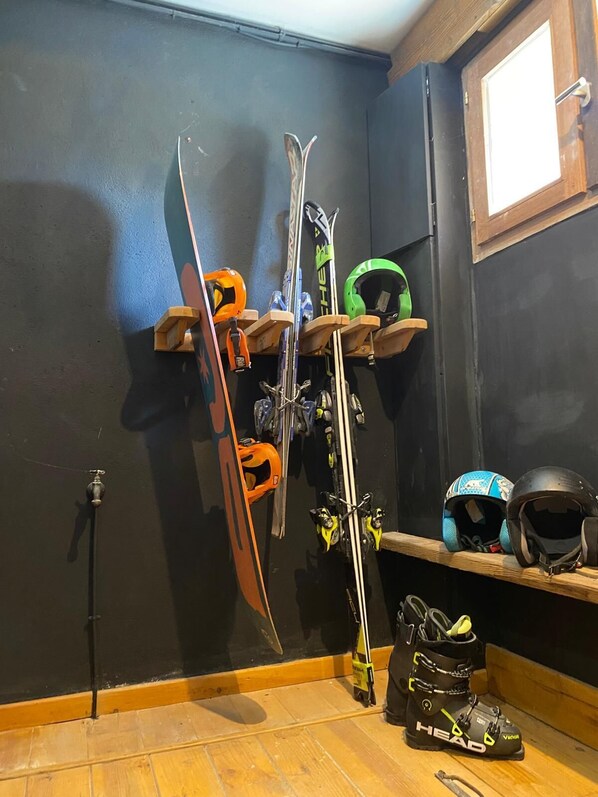 Ein Skiraum mit auf Holzgestellen platzierten Skiern und Helmen.