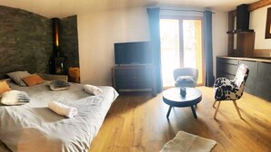 Une chambre avec un grand lit, une télévision, une petite table ronde et une chaise.