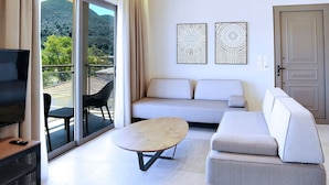 Habitación de hotel moderna con techo de madera, sofá, televisor y balcón con vistas a las montañas.