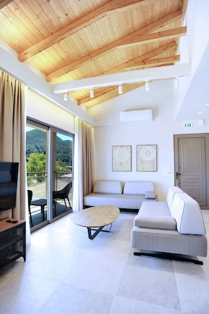 A modern hotel room with a wooden ceiling, a sofa, a round table, and a TV. - Demar Suites Vlycho Lefkada (Lefkada)
