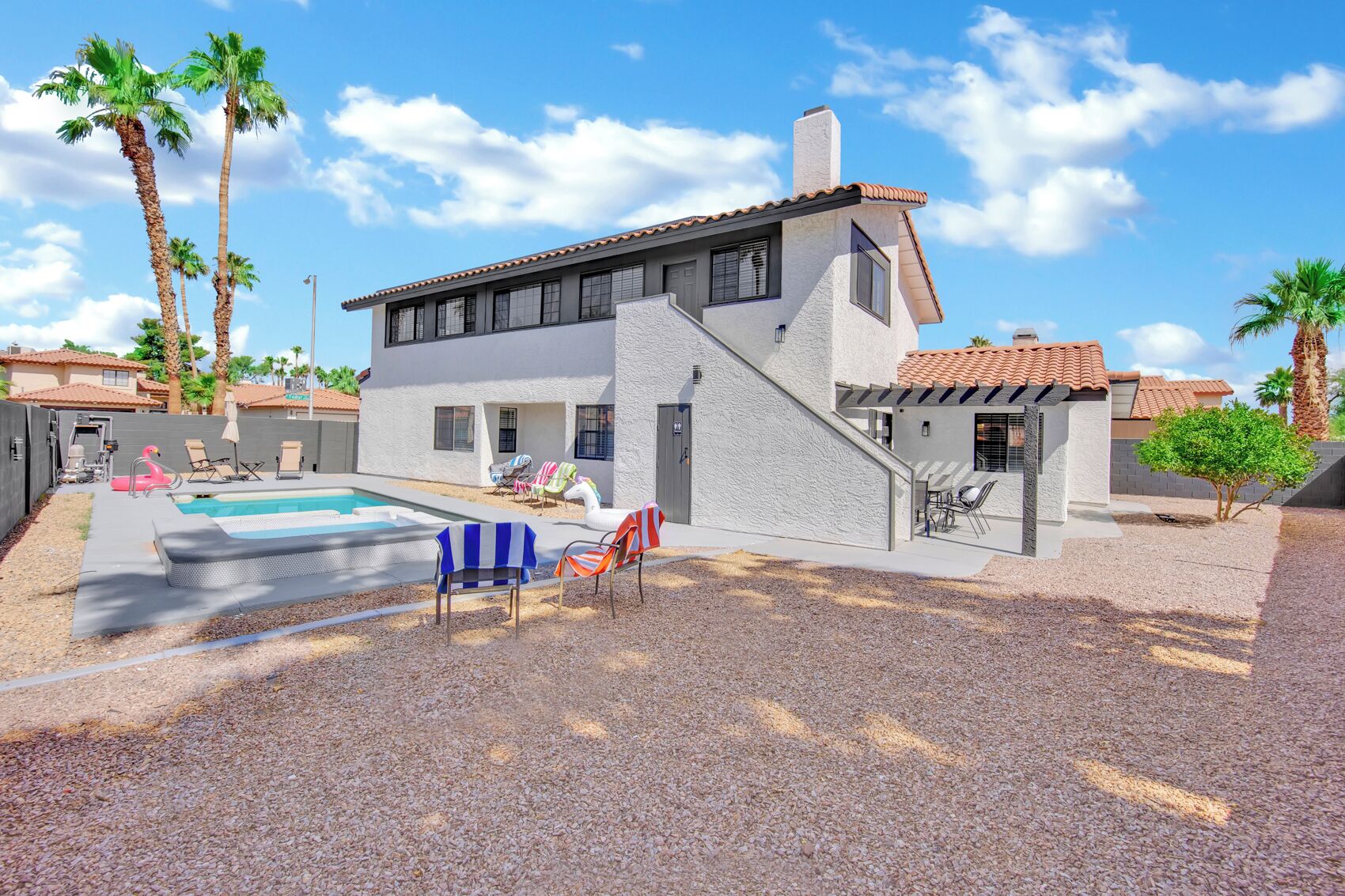 Une maison moderne dotée d’une piscine, d’un espace salon extérieur et de palmiers.