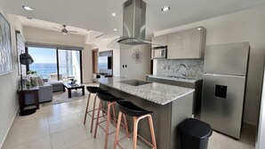 A modern kitchen with a large island, stainless steel appliances, and a view to the outside. - Altomare hermoso depa con vista al mar (Mazatlán)