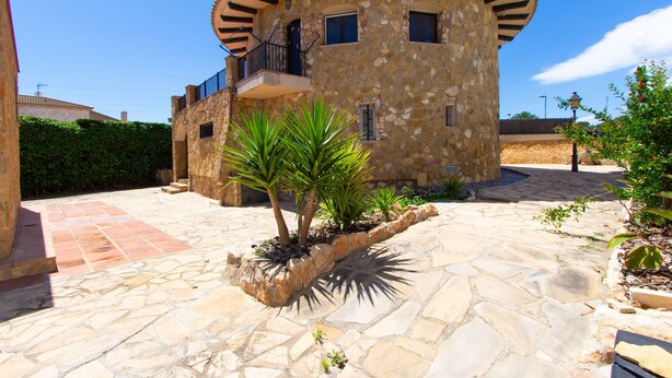 A stone building with a circular tower, a balcony, and a stone patio with plants. - Incredible & Unique Costa Dorada Abode! (Creixell)
