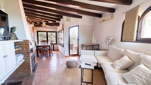 A spacious living area with a white sofa, a small table, and a brick fireplace. - Incredible & Unique Costa Dorada Abode! (Creixell)