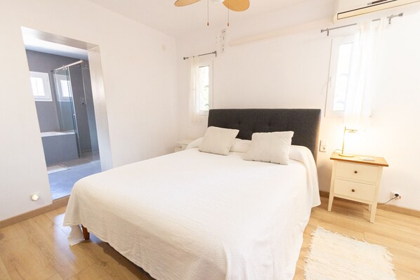 A bedroom with a bed, bedside table, and a door leading to a bathroom.