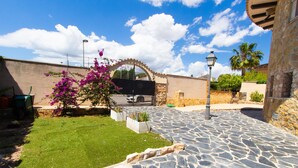 A courtyard with a stone pathway, a grassy area, and a gate with a decorative arch. - Incredible & Unique Costa Dorada Abode! (Creixell)