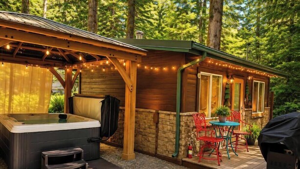 A wooden cabin with a hot tub, outdoor seating, and string lights. - Romantic Small Cabin in the Woods. Fireplace,Hot tub,A/C,Firepit,WiFi, Mt Rainer (Ashford)