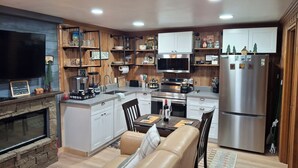A modern kitchen with a central island, built-in appliances, and a cozy seating area with a fireplace. - Romantic Small Cabin in the Woods. Fireplace,Hot tub,A/C,Firepit,WiFi, Mt Rainer (Ashford)