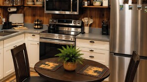 A modern kitchen with stainless steel appliances, wooden cabinets, and a round dining table with chairs. - Romantic Small Cabin in the Woods. Fireplace,Hot tub,A/C,Firepit,WiFi, Mt Rainer (Ashford)