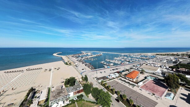 An aerial view of a coastal town with a marina, beach, and clear blue sky.