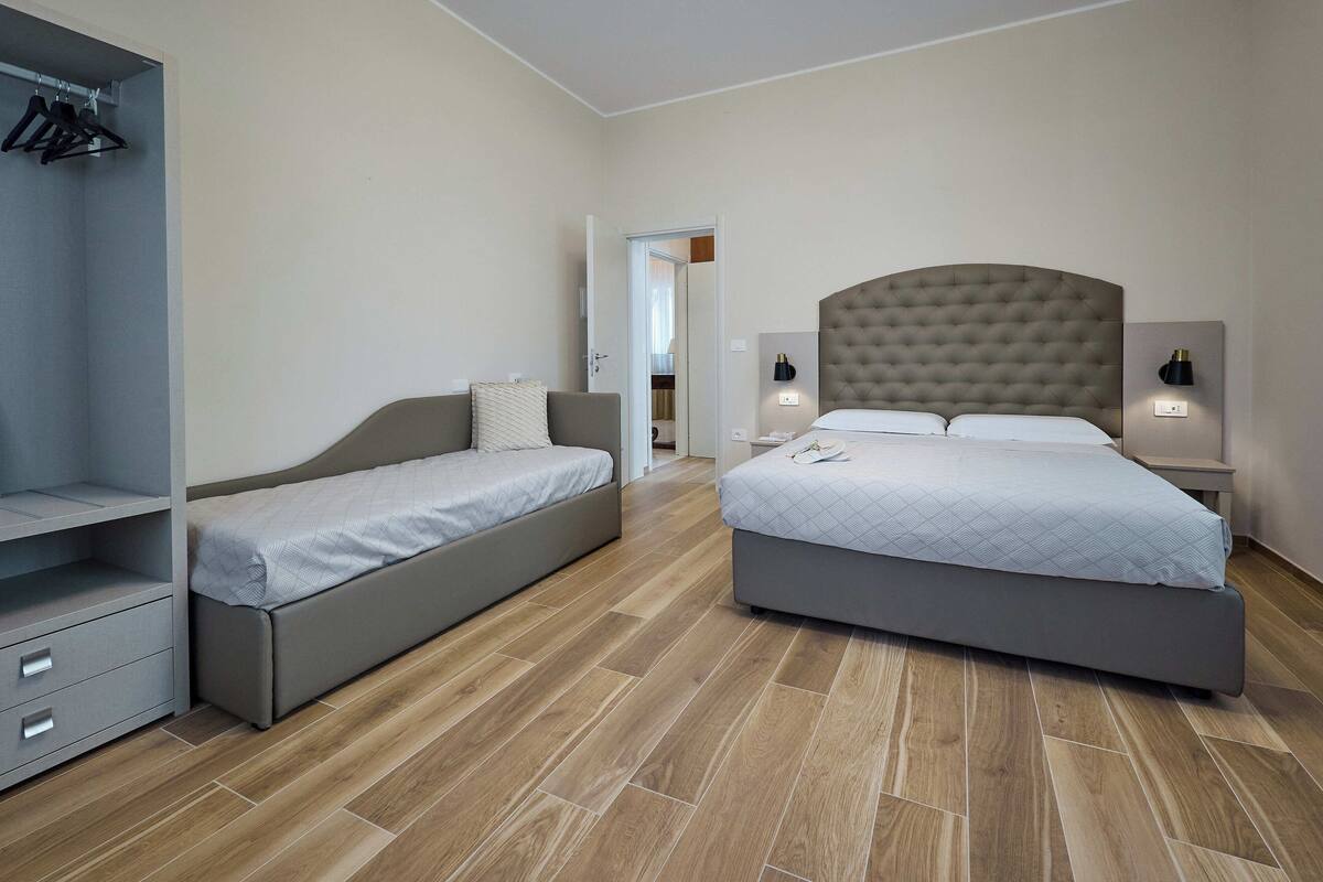 A bedroom with two beds, a wardrobe, and a mirror.