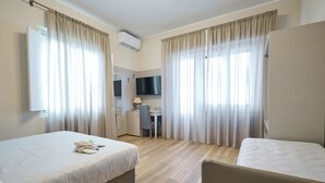 A hotel room with two beds, a desk, a chair, a TV, and curtains.
