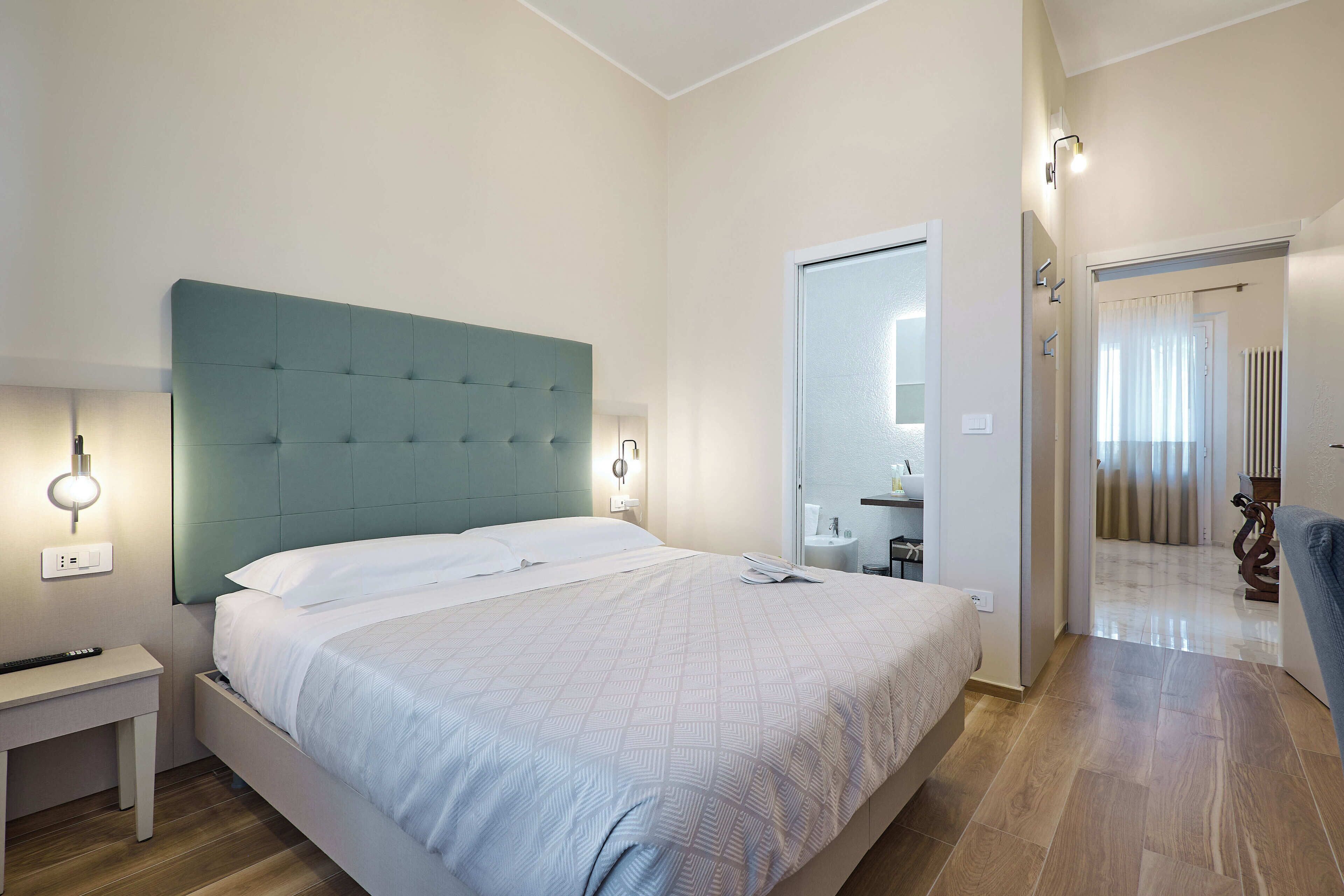 A bedroom with a bed, bedside table, and a mirror.