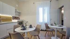 A modern kitchen with white cabinets, a microwave, and a dining area with a round table and chairs.