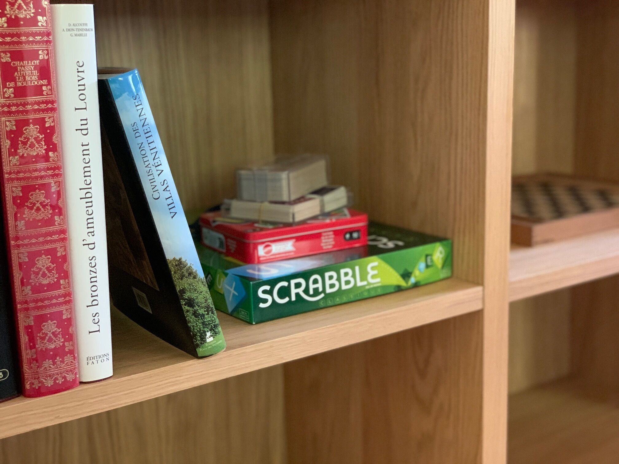 A bookshelf with books and a Scrabble game box.