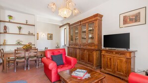 Ein Wohnzimmer mit rotem Ledersofa, Holzschrank und Fernseher.