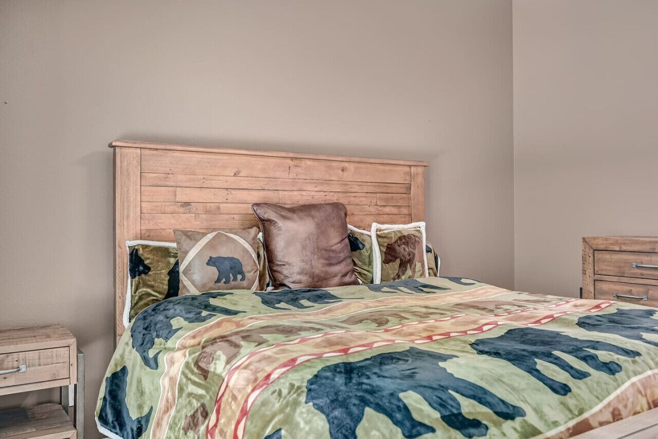 Een slaapkamer met een houten hoofdbord, een bed met een geborduurd sprei en een nachtkastje met lades.