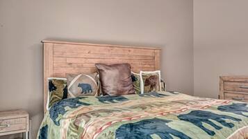 Een slaapkamer met een houten hoofdbord, een bed met een geborduurd sprei en een nachtkastje met lades.