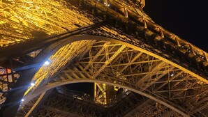 La Torre Eiffel iluminada de noche, mostrando su intrincada estructura de hierro.