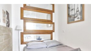Un dormitorio con cama, cabecera de madera, lámpara y un cuadro en la pared.