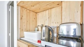 Una kitchenette compacta con paredes de madera, un lavamanos de acero inoxidable, un hervidor y un tostador.