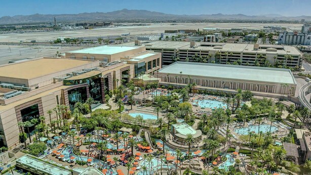 A resort with multiple swimming pools, palm trees, and a view of the airport in the background. - MGM Signature- Lazy River Jacuzzi Work Desk Studio (Las Vegas)