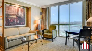 A hotel room with a large window, a sofa, a chair, a small table, and a painting on the wall. - MGM Signature- Lazy River Jacuzzi Work Desk Studio (Las Vegas)