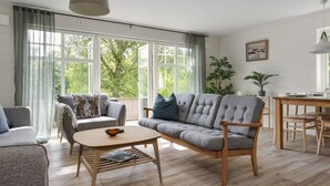 A living room with a sofa, armchair, coffee table, and dining table. - Lakeview spacious family home (Västra Götalands län)