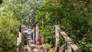 A wooden staircase leading to a building with a red roof, surrounded by dense greenery. - Lakeview spacious family home (Västra Götalands län)