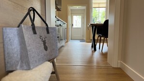 Un couloir avec un banc, une table entourée de chaises et une porte donnant sur une autre pièce.