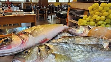 A seafood display with various fish and a bunch of yellow grapes in a restaurant setting.
