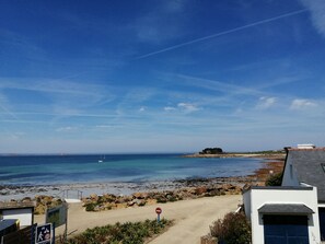 A beach view with a clear sky, a sandy path, and a rocky shoreline. - A Bord de mer ! Grande Maison Face à la mer (Plougasnou)