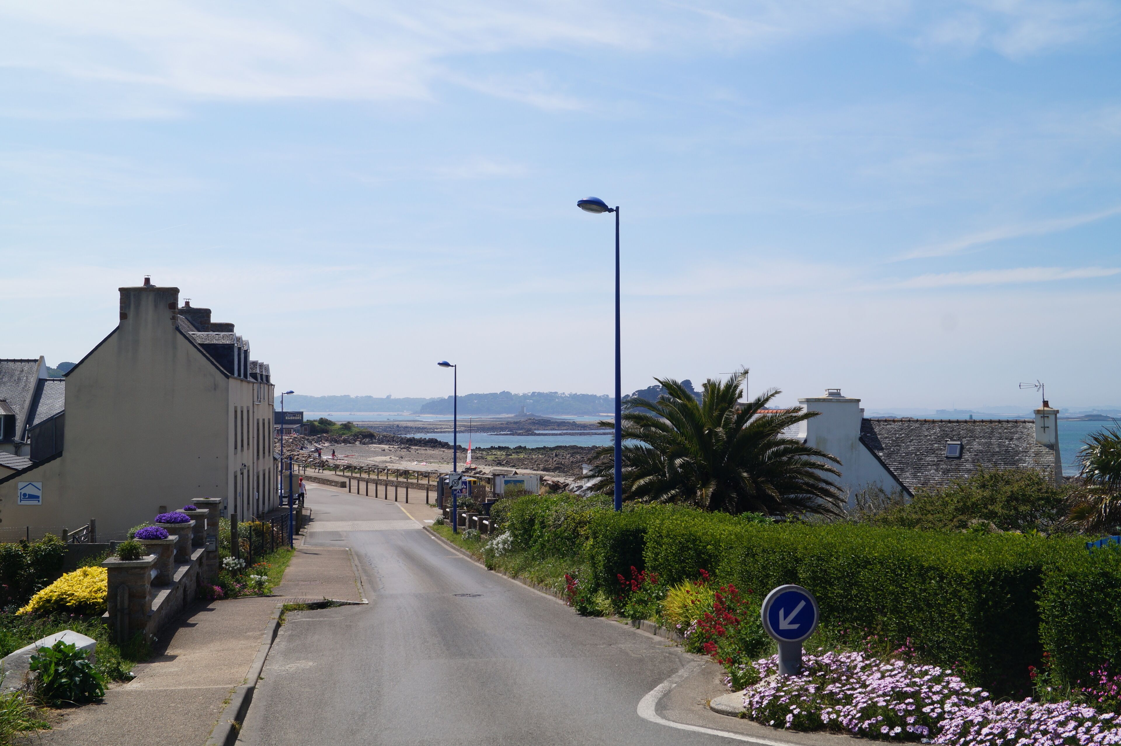 Eine Küstenstraße mit Gebäuden an einer Seite und einem Strand an der anderen.