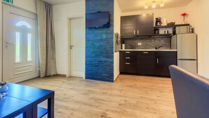 Una cocina moderna con armarios oscuros, una pared de acento azul y un televisor de pantalla plana montado sobre la encimera.