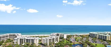 A coastal hotel complex with multiple buildings, a beach, and a view of the ocean.