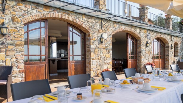 A stone building with a dining area set up for breakfast. - Agriturismo Cima alla Serra (Buti)