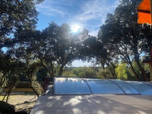 Un espace extérieur abrité, doté d’un toit transparent, entouré d’arbres et offrant une vue sur un ciel dégagé.