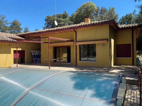 Un bâtiment jaune doté d’un patio couvert, d’une piscine et d’une antenne parabolique.