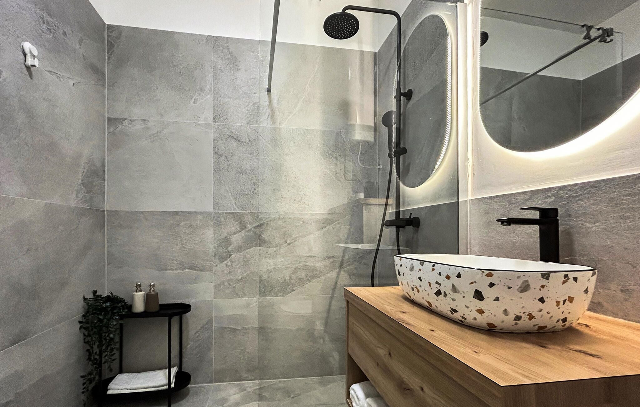A modern bathroom with a freestanding bathtub, a large mirror, and a wooden vanity with a unique sink.