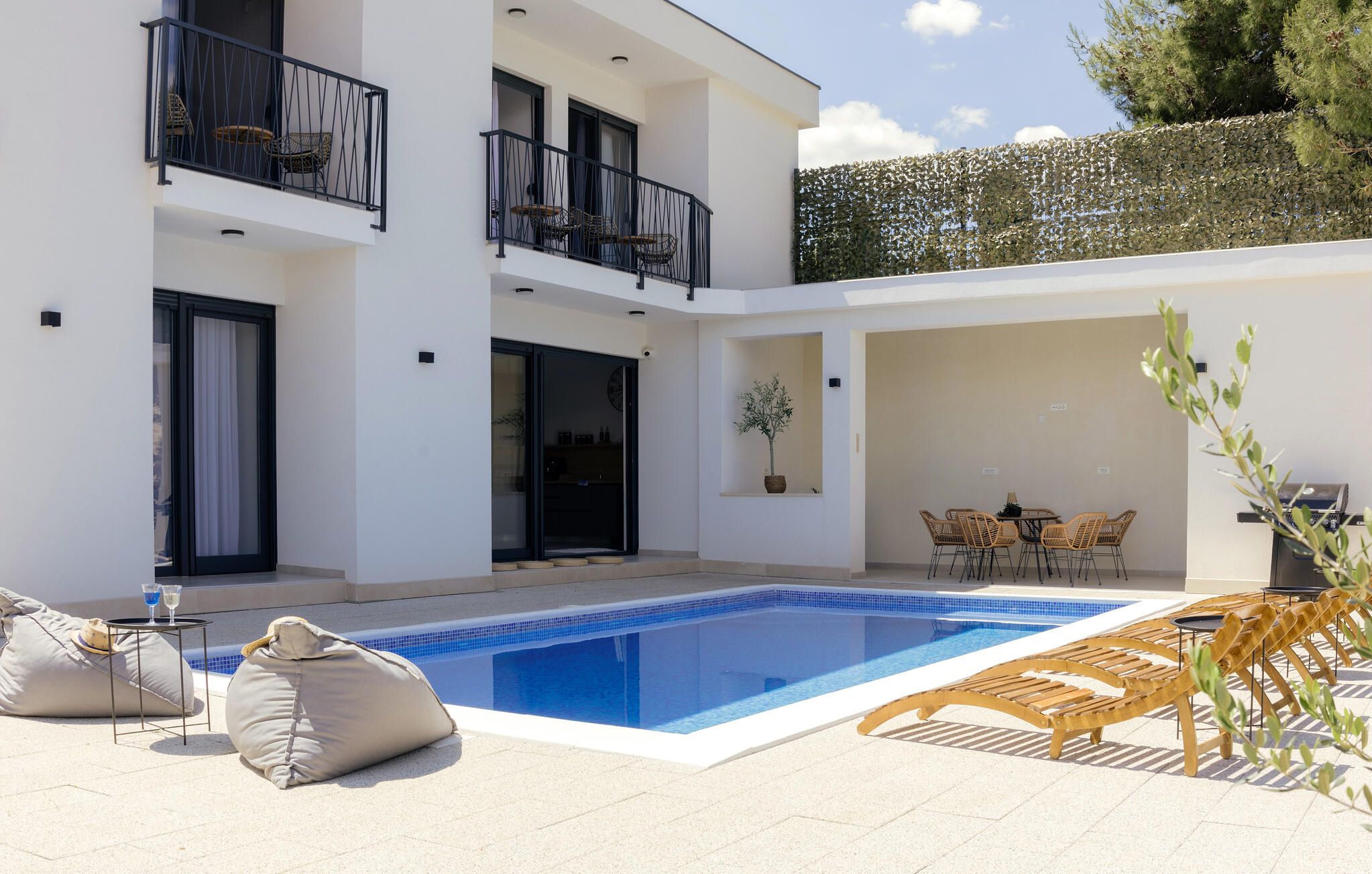 Un bâtiment moderne à deux étages doté d’une piscine, d’un espace extérieur aménagé et d’un patio couvert.