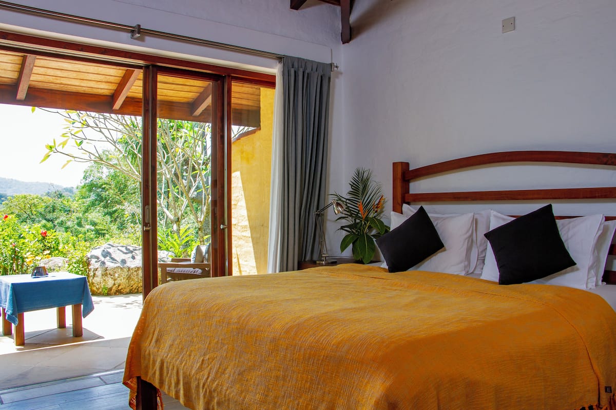 A bedroom with a large bed, a wooden headboard, and a view of the outdoors.