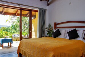 A bedroom with a large bed, a wooden headboard, and a view of the outdoors. - Bougainvillea Retreat  (Maberiyatenna)