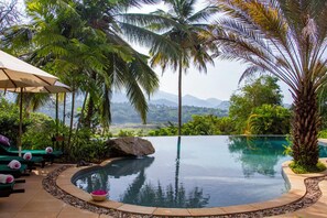 An infinity pool with a view of mountains, surrounded by palm trees and lounge chairs. - Bougainvillea Retreat  (Maberiyatenna)