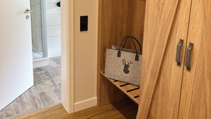Een houten garderobe met een spiegeldeur en een klein plankje met tassen, en een deur naar een badkamer.