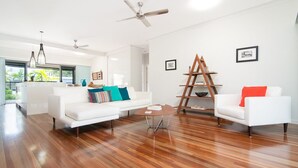 A modern living room with white sofas, a coffee table, and a ladder against the wall.