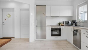 Una cocina moderna con armarios blancos, electrodomésticos de acero inoxidable y un ventanal con vistas.