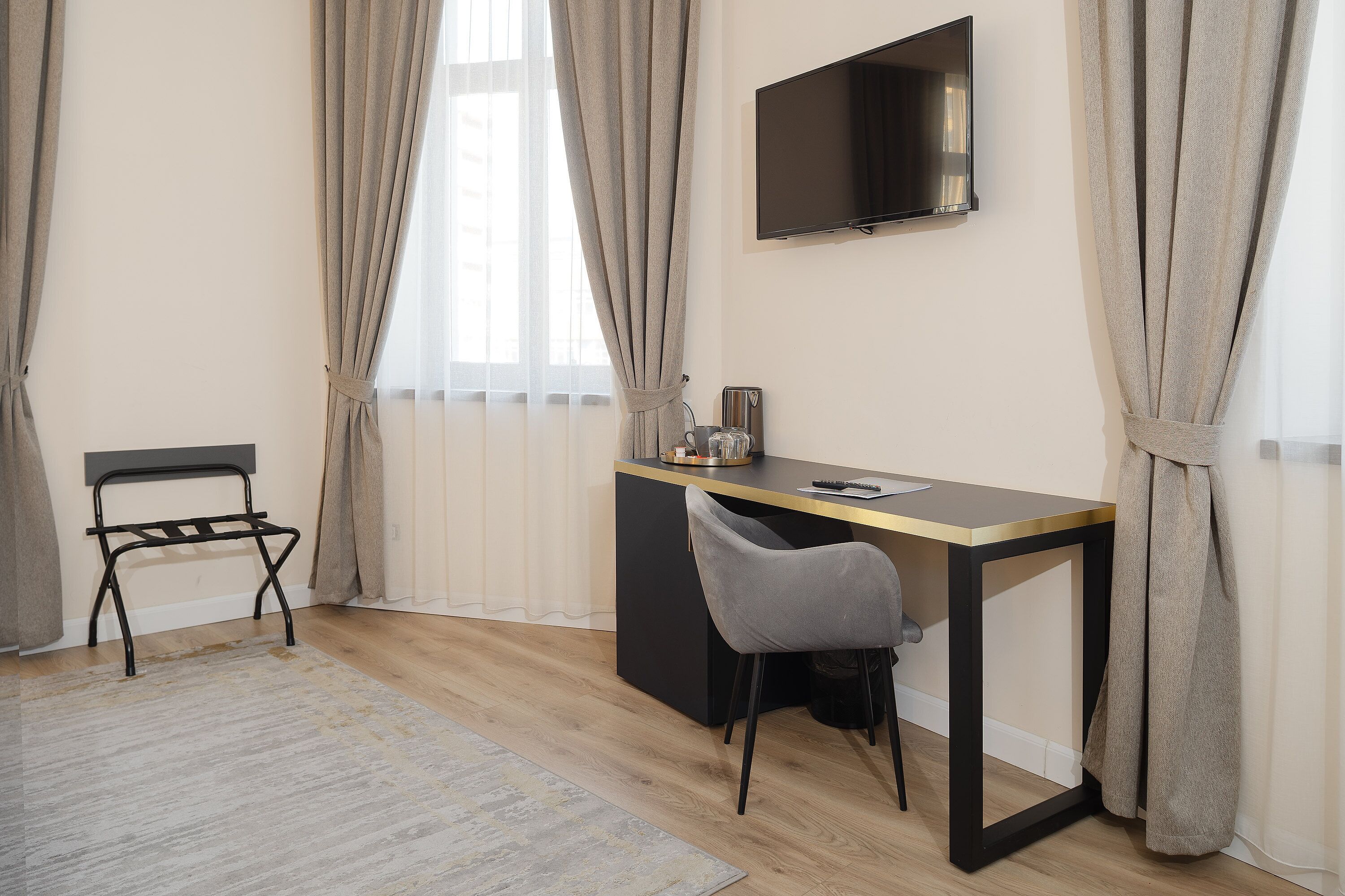 A modern room with a desk, chair, and a TV mounted on the wall.