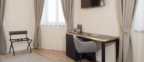 A modern room with a desk, chair, and a TV mounted on the wall.
