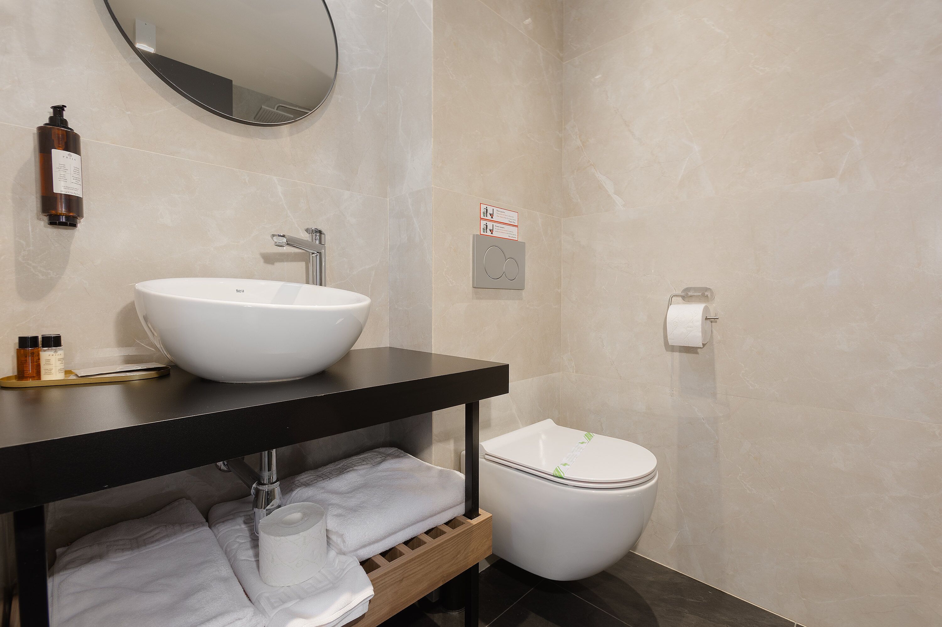 A modern bathroom with a white sink, black countertop, and a toilet.